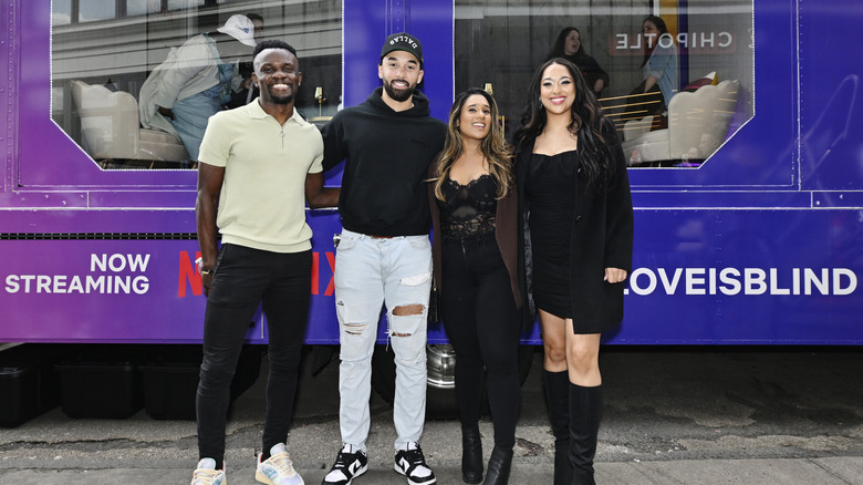 "Love Is Blind" cast members Kwame Appiah, Bartise Bowden, Deepti Vempati, and Bliss Poureetezadi standing in front of promotional pods on street