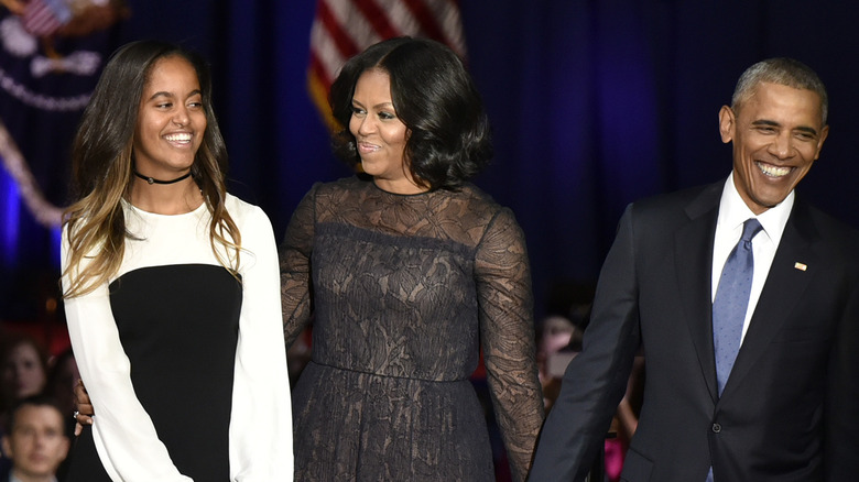 Malia, Michelle, Barack Obama standing together smiling