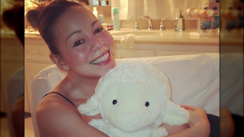 Mariah Carey smiling, holding toy lamb