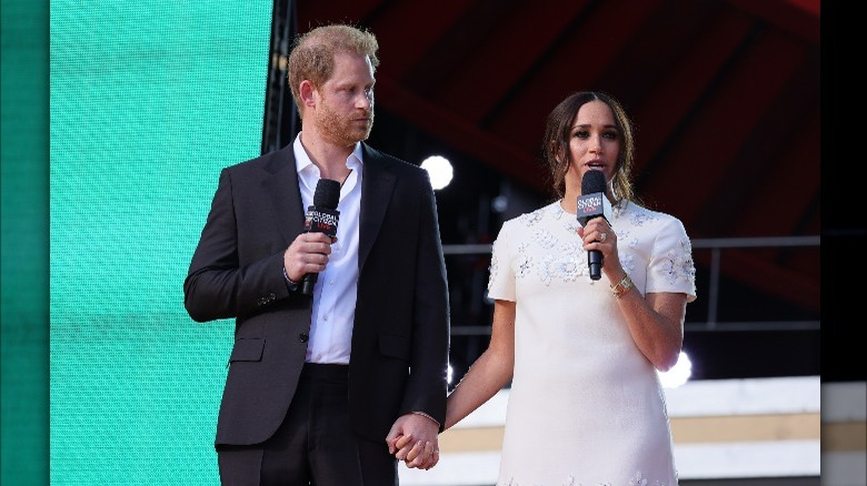 Prince Harry and Meghan Markle holding hands on stage