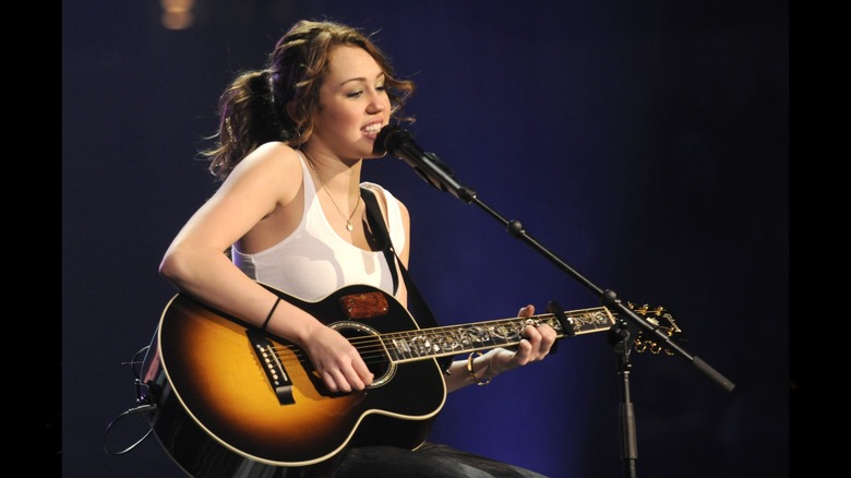 Miley Cyrus playing guitar and singing