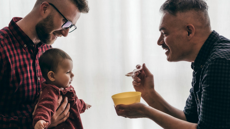 men feeding baby with spoon