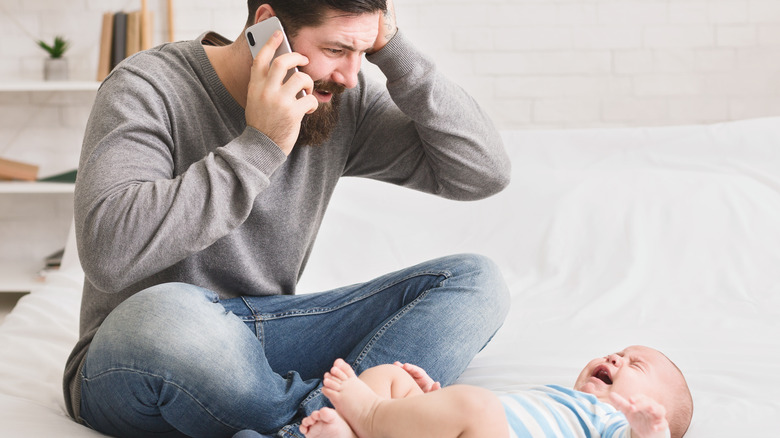 man upset on phone with crying baby