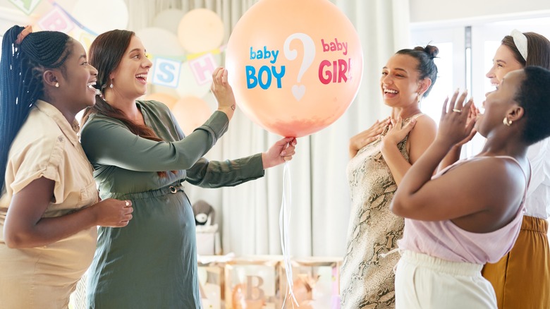 women celebrating gender reveal balloon