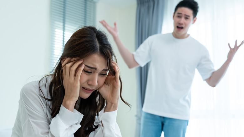 Woman in distress as man talks emphatically in the background