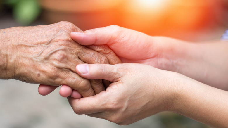 Younger person holding elder's hand