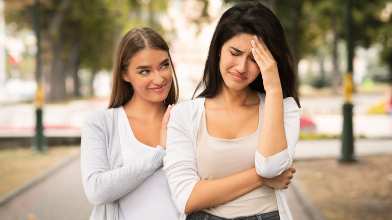 smiling woman with upset friend