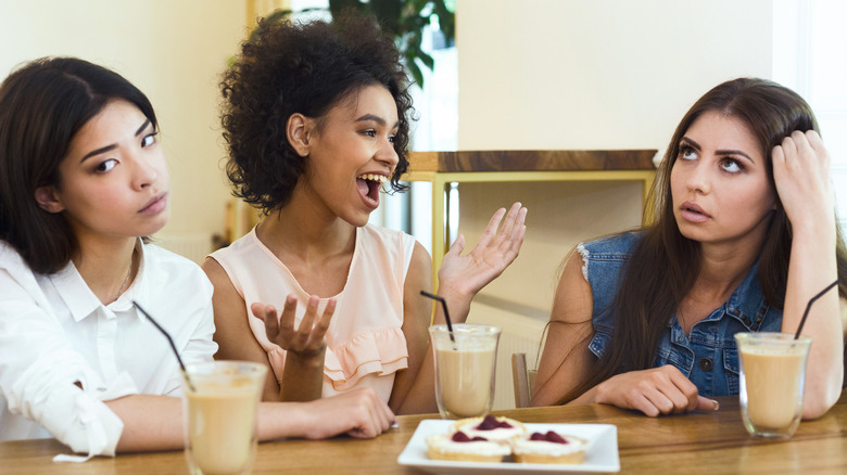 two women look annoyed while third woman talks