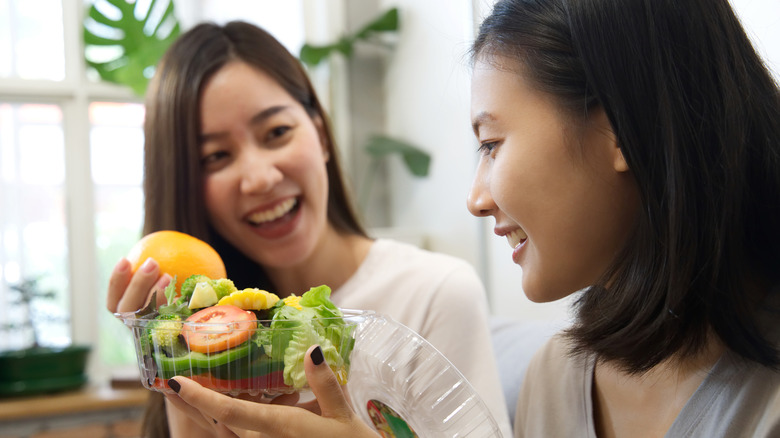 woman showing a salad to friend