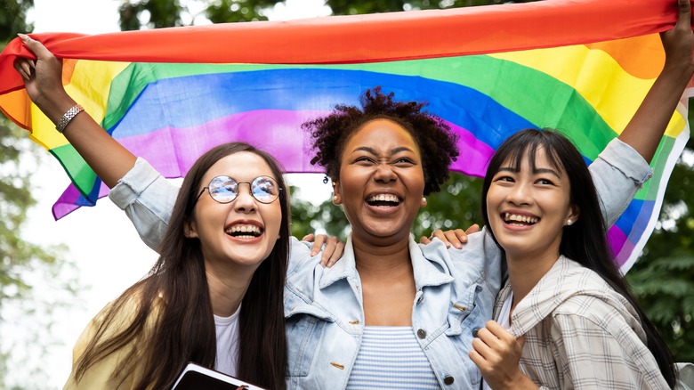 Three women smiling with pride flag