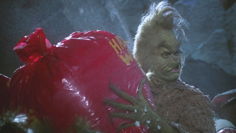 The Grinch holding a red garbage bag 