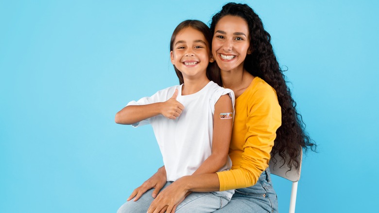 Kid sitting on mother's lap after getting vaccinated