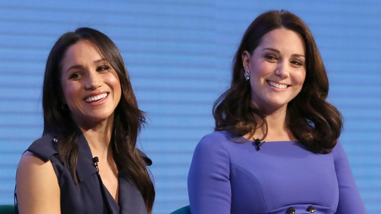 Meghan Markle and Kate Middleton smiling onstage