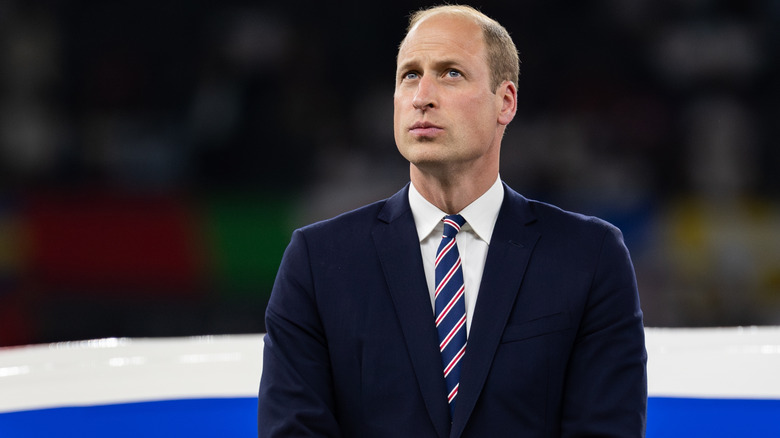 Prince William purses his lips and looks up in a suit