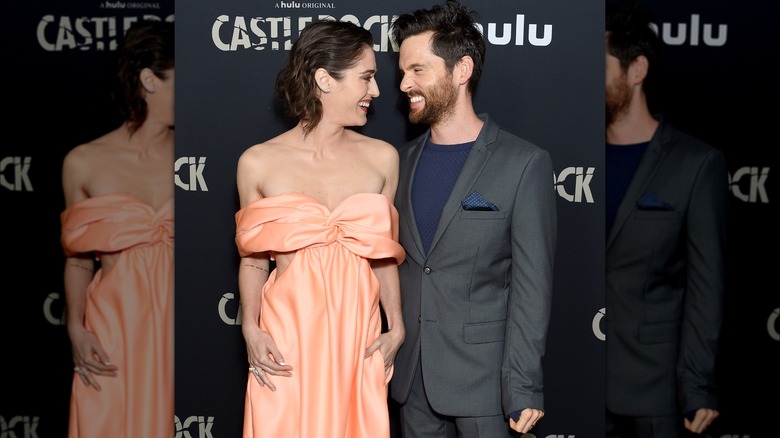 Lizzy Caplan and Tom Riley smiling at one another