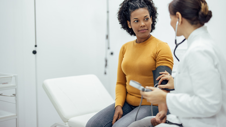 Woman having blood pressure taken at doctor