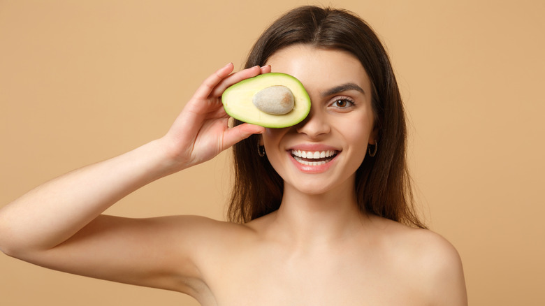 woman with healthy hair holding an avocado