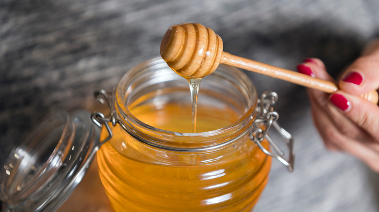 woman holding jar of honey