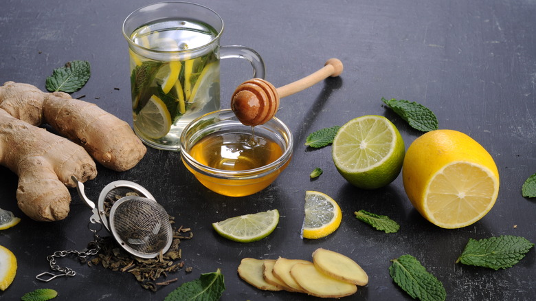 honey surrounded by lemons, ginger, and tea