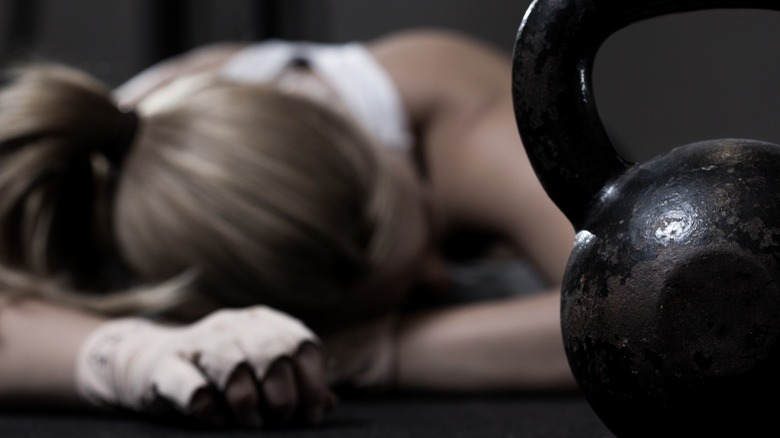 woman exhausted from exercise on floor behind kettlebell