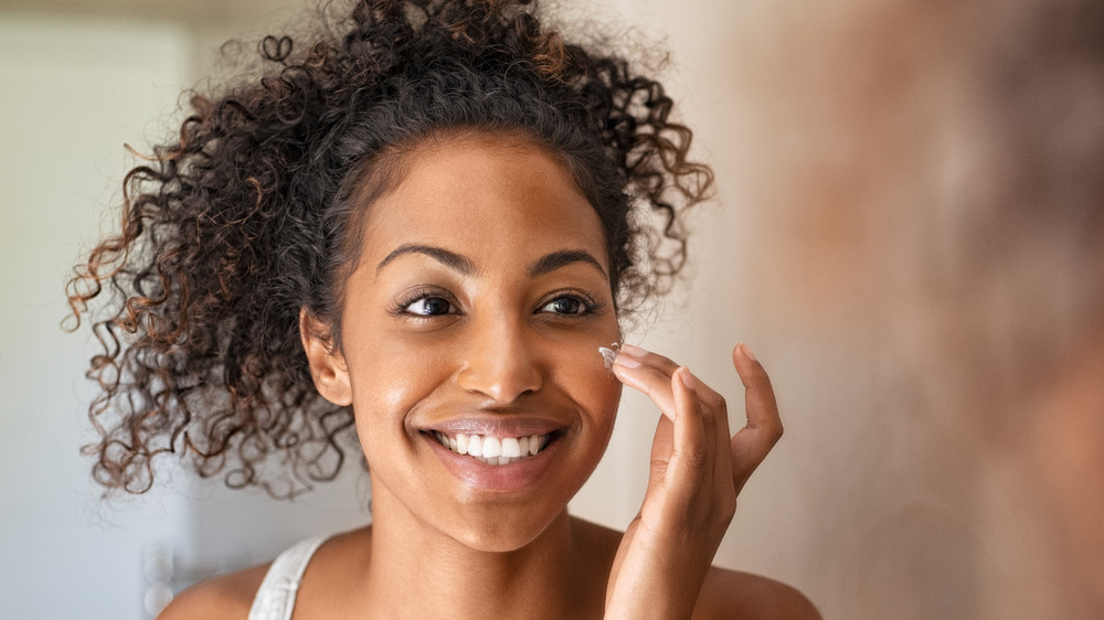 A woman applying cream on her face