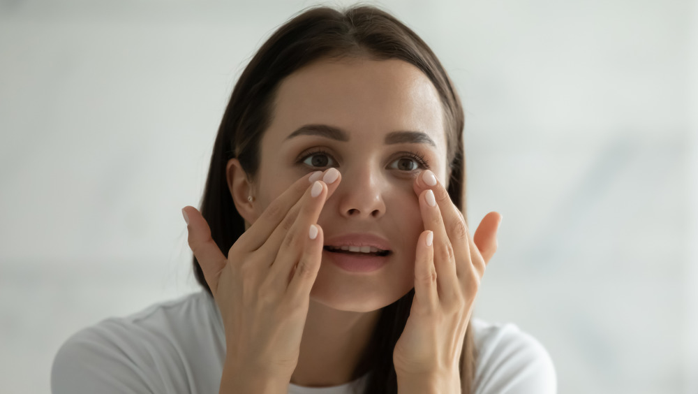 A woman putting on eye cream