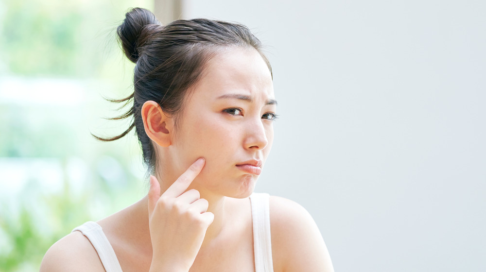 A woman looking at a spot on her face