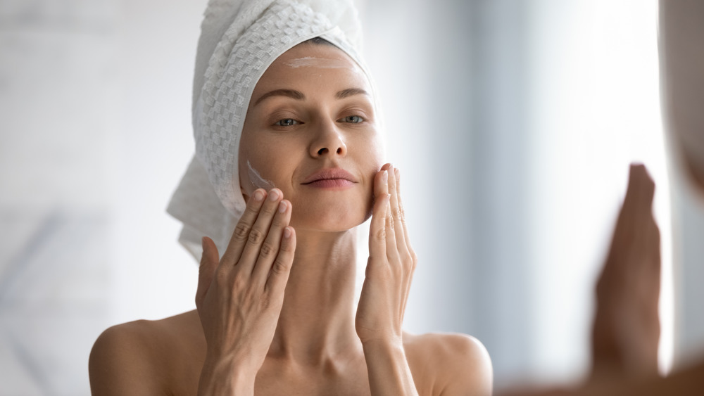 A woman putting moisturizer on her face