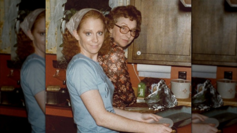 A young Reba McEntire stands in the kitchen with her mother