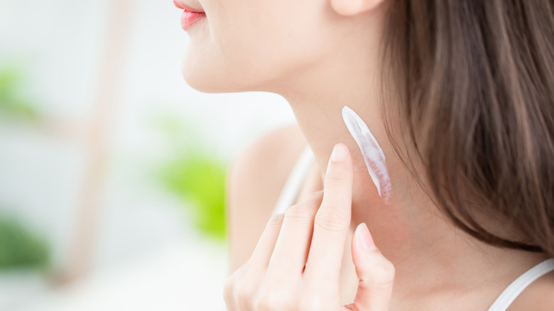 Woman applying cream to her neck