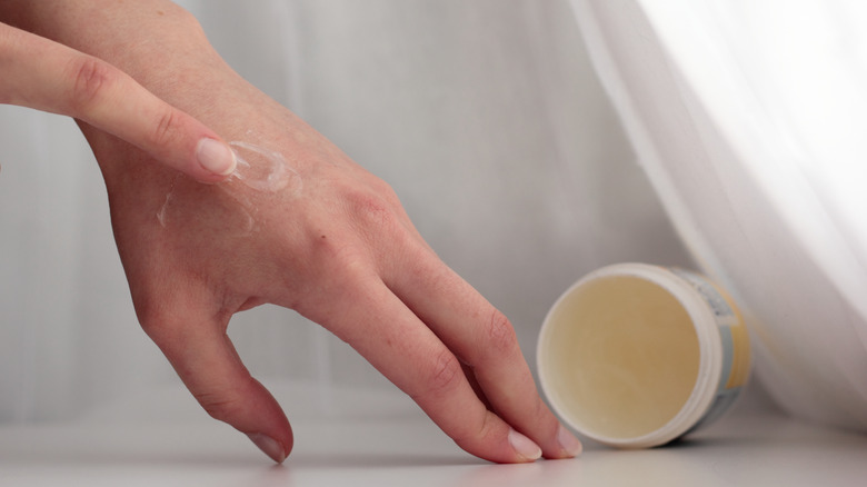 A person applying petroleum jelly to the skin