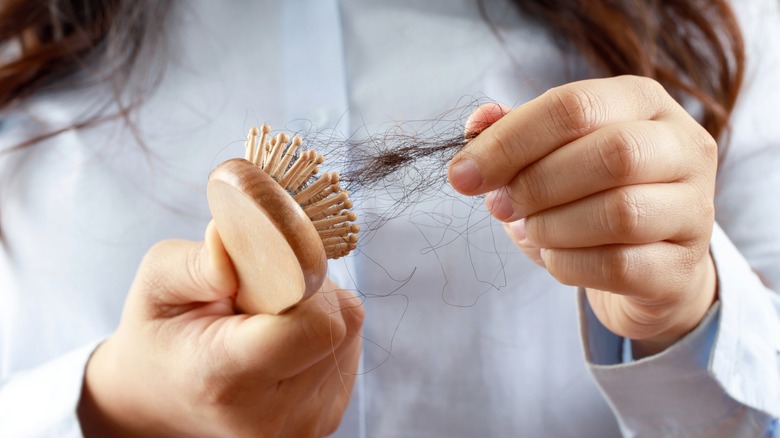 woman pulling hair out of brush bristles