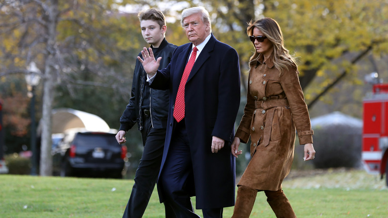 Barron, Donald, and Melania Trump walking across lawn