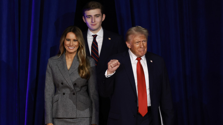 Barron Trump standing between his mother and father on stage