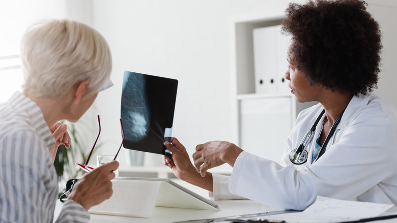 A doctor examines a mammogram image with her patient