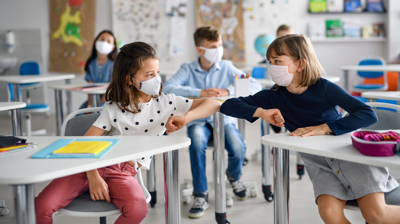 children bump elbows in classroom