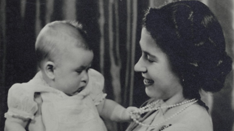 Baby King Charles grabbing Queen Elizabeth's pearls and Elizabeth smiling at him