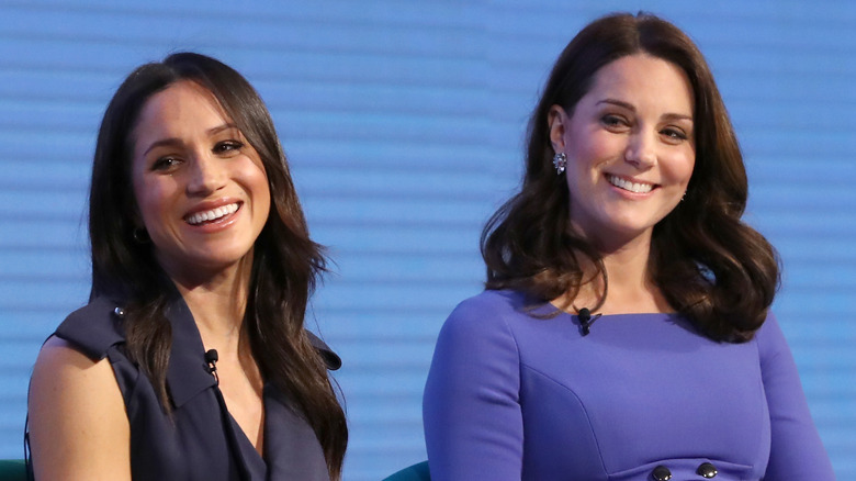 Meghan Markle and Kate Middleton smiling onstage