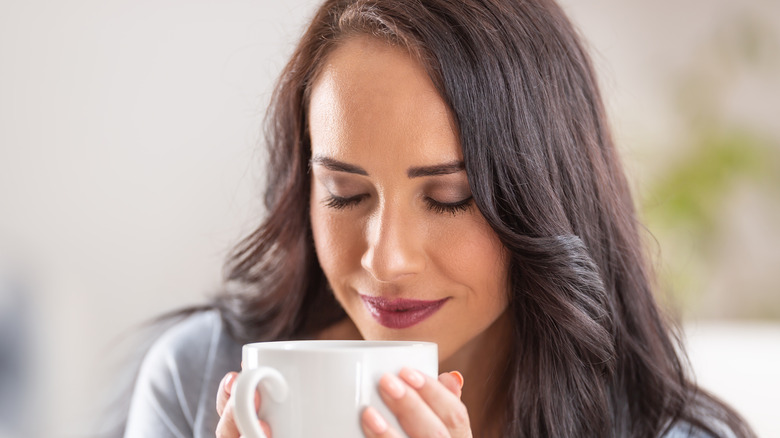 woman smiling sipping coffee mug