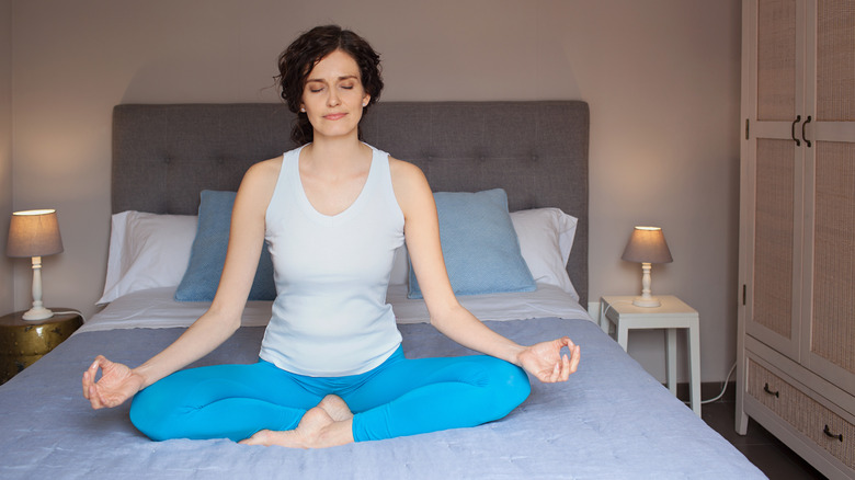 woman meditating on bed