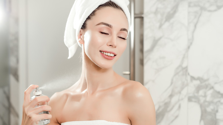 Woman spraying perfume after shower