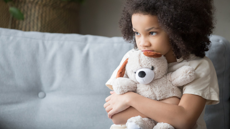 Sad girl hugging teddy bear