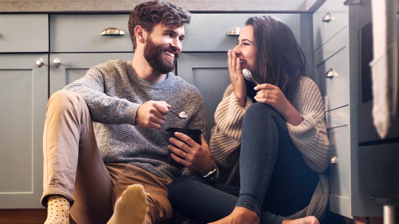 man and woman eating ice cream on kitchen floor