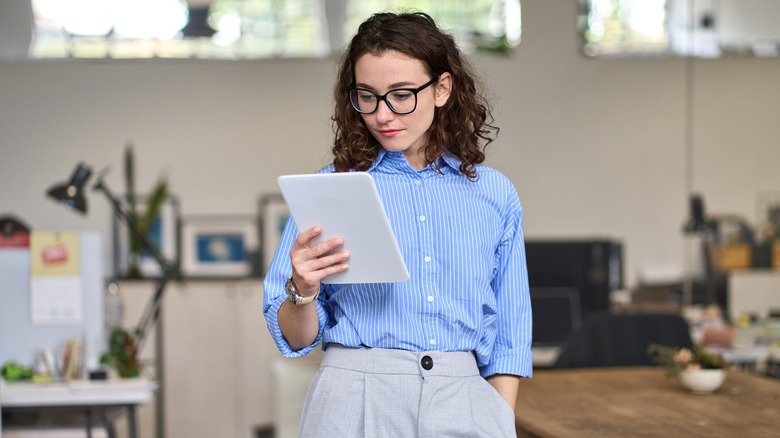 A woman holding a tablet at the office.