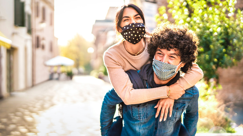 Couple wearing masks, woman on man's back