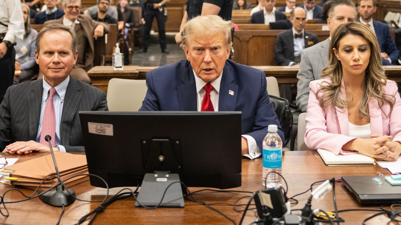 Donald Trump sitting in courtroom with attorneys on either side