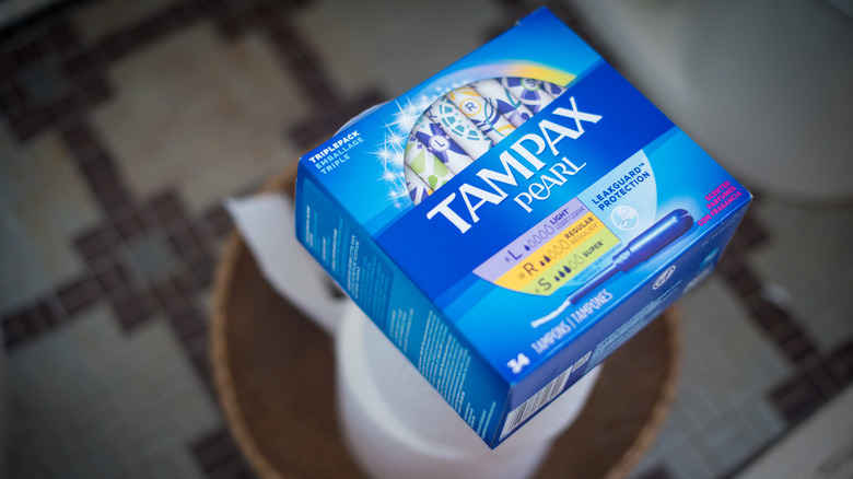 boxes of tampon brand Tampax on top of a roll of toilet paper