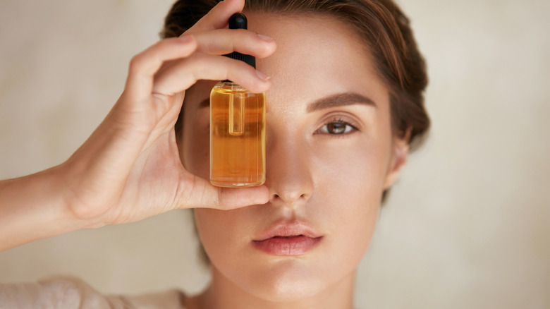 Woman holding up a bottle of oil