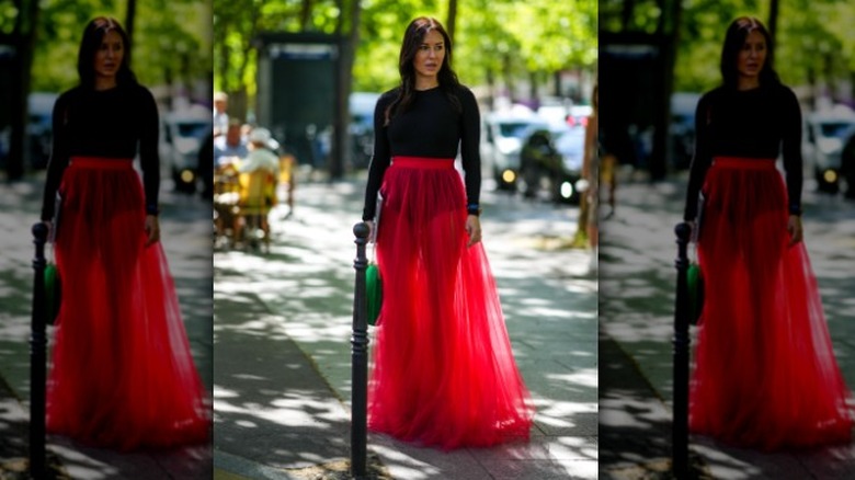 Woman in a black bodysuit and red skirt