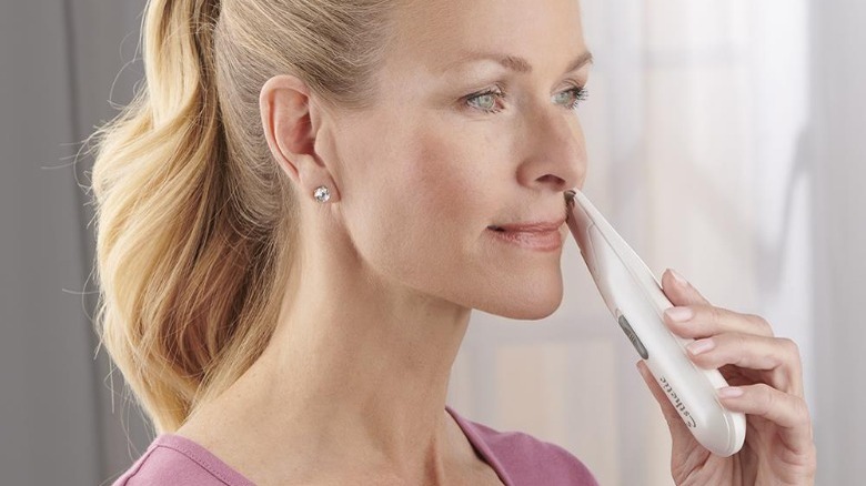 woman using epilator on face